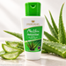 Golden Heart Aloe Vera Premium BalsamGel mit 98 % Aloe Vera Gel aus Bio-Anbau in weißer Flasche mit grünem Verschluss auf heller Steinoberfläche, umgeben von frischen Aloe Vera Blättern und aufgeschnittenen Blattstücken mit transparentem Gel.