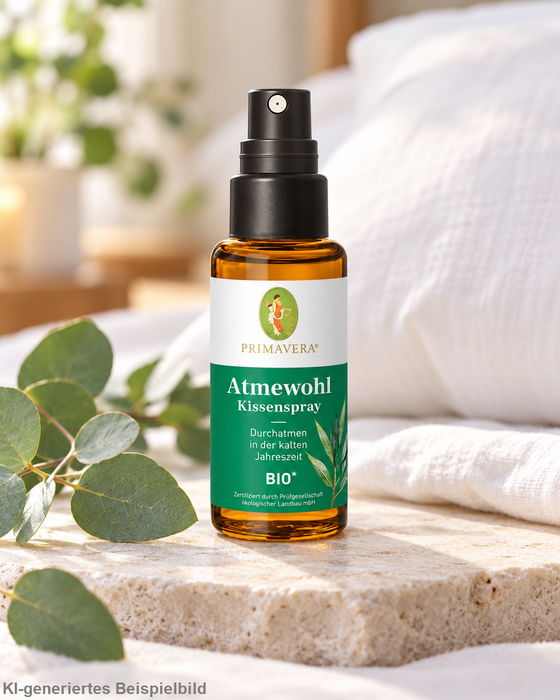 Primavera Atmewohl Kissenspray bio 30 ml in brauner Sprühflasche, dekoriert mit Eukalyptusblättern auf hellem Naturstein in einem ruhigen, hellen Spa-Ambiente.