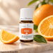 Young Living Orange ätherisches Öl 5 ml neben frischen Orangenscheiben und grünen Blättern auf heller Steinoberfläche.