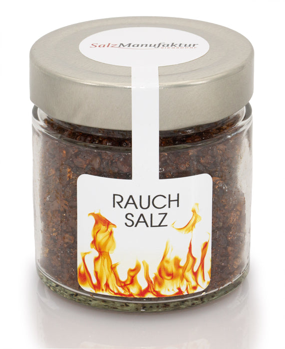 Kaltgeräuchertes Rauchsalz der SalzManufaktur in einem klaren Glas mit Metalldeckel und Flammenetikett, freigestellt vor weißem Hintergrund.